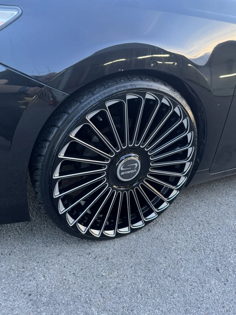 Close-up of a multi-spoke aftermarket wheel on a dark vehicle.