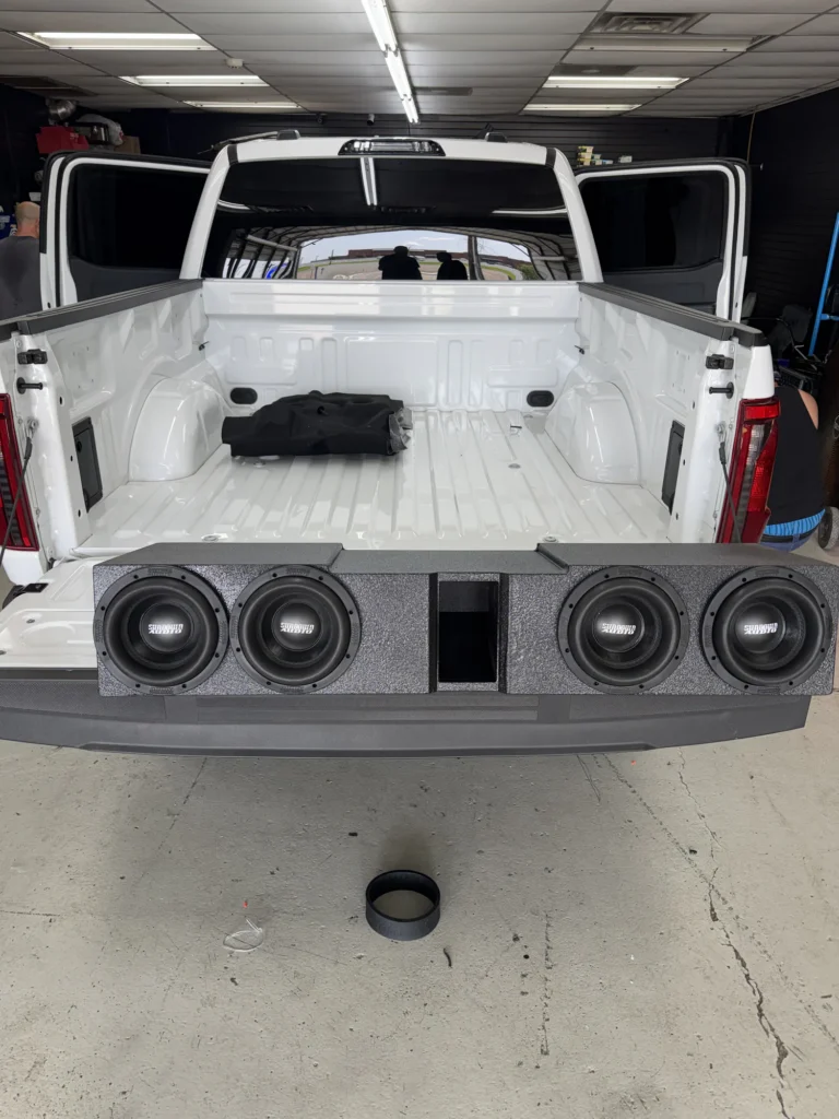 Custom subwoofer enclosure installed behind a pickup tailgate.