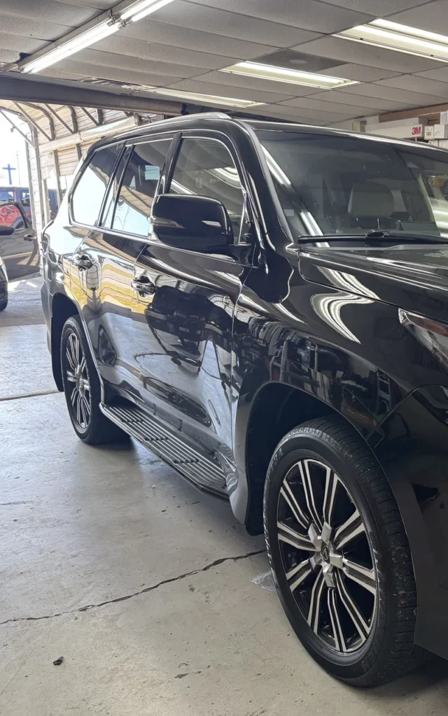 Black Lexus SUV with aftermarket wheels inside the installation shop.