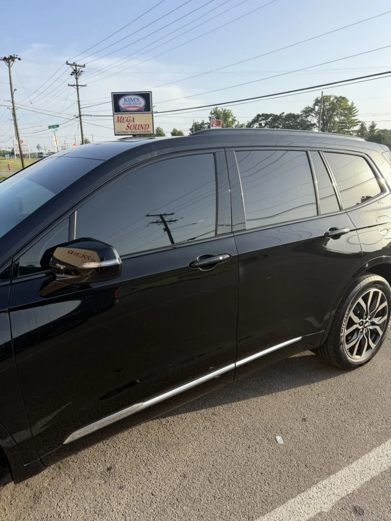 Black SUV with dark window tint parked outside Mega Sound.